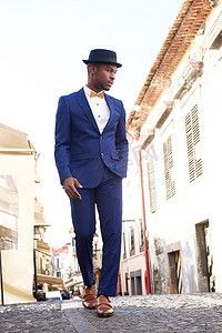 穿着复古西装和帽子的全身非洲裔美国男模在城市中行走