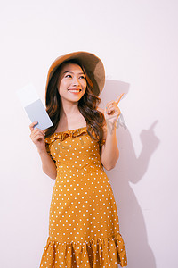 快乐的年轻女性站在粉红色背景中，出示带机票的护照
