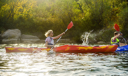 快乐的太阳摄影照片_年轻快乐的夫妇在美丽的河流或湖泊上划皮划艇