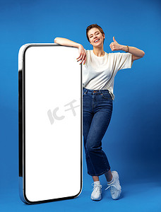 快乐的年轻女人靠着巨大的手机，屏幕是空白的，为了你的广告，模拟