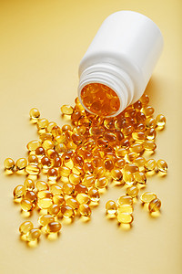 黄色背景中从罐子里倒出的金色 Omega-3 鱼油胶囊