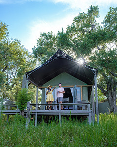一对男女在豪华野生动物园的野生动物园帐篷前，南非，灌木丛中的豪华野生动物园旅馆