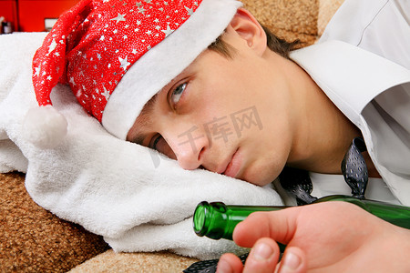 醉酒男人摄影照片_戴着圣诞老人帽子的醉酒少年