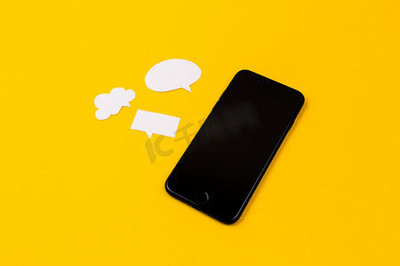 泡泡云摄影照片_黄色背景上带有纸泡泡的智能手机。