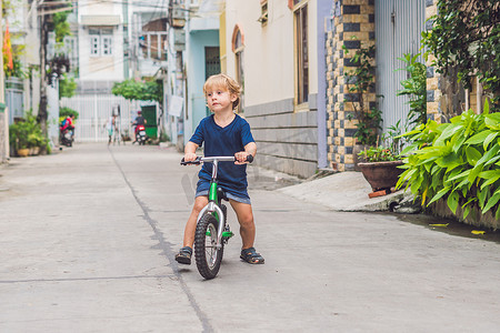 活跃的金发小孩男孩在城市的街道上驾驶自行车。