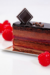白色背景中的一块巧克力蛋糕，上面有通风的慕斯和覆盆子果冻