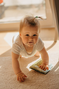 太阳光线摄影照片_一个好奇的 7 个月小女孩从阳台门爬出家里的紧身连衣裤。