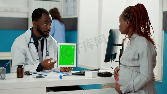 男性产科医生展示带绿屏的数字平板电脑