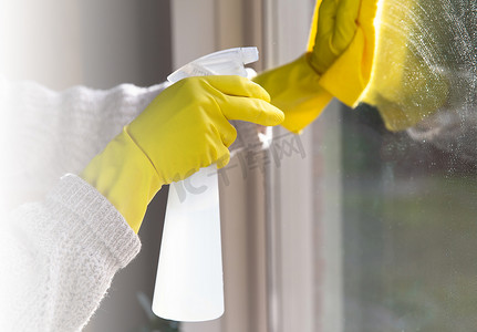 用喷雾洗涤剂、黄色橡胶手套和洗碗布在工作表面概念上清洁窗户，以实现卫生、商业和健康概念