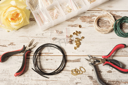 工作区配有制作珠宝的工具 - 钳子、皮革、耳环和手镯、项链。