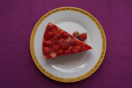 一块美味的草莓蛋糕，上面有果冻和草莓，放在漂亮的盘子上，俯视