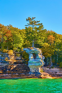 画有绿水的岩石和一棵树在高大的雕刻岩石上，树根作为桥梁
