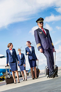 成熟飞行员与三名年轻漂亮空姐在机场对抗飞机的肖像