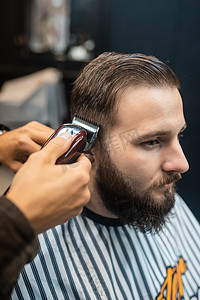 男士发型摄影照片_理发店师傅用理发器为男士理发