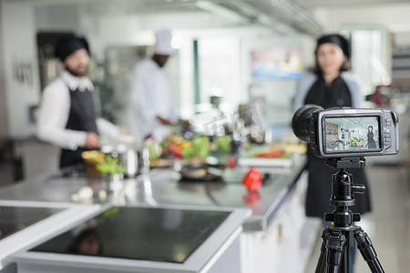 摄像机记录厨师在餐厅厨房烹饪美食的选择性焦点，用于在线烹饪学校课程。
