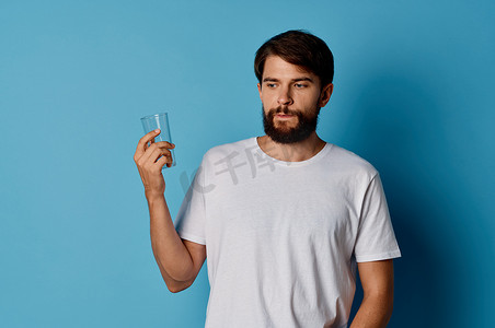 男人在蓝色背景生活方式饮料裁剪视图中的玻璃杯中测试水