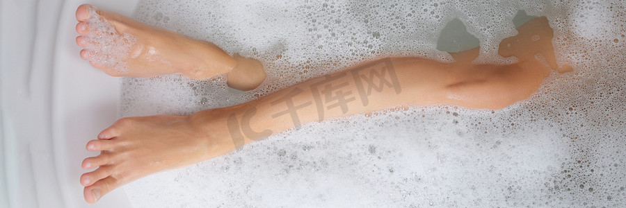 细长的女性腿在浴缸里用肥皂水