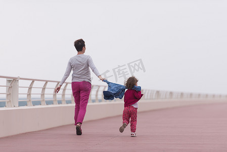 海边长廊上的妈妈和可爱的小女孩