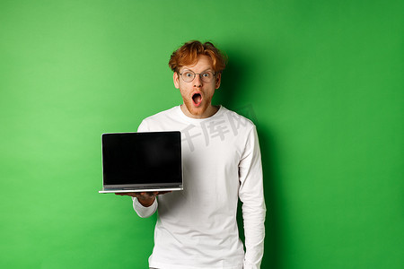 看到在线促销后，戴着眼镜的红头发男人印象深刻，他展示笔记本电脑屏幕，难以置信地盯着镜头，站在绿色背景上