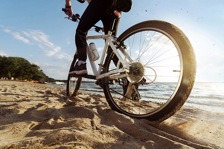 勿忘初心奋力前行摄影照片_骑自行车的人沿着沙滩缓缓前行。