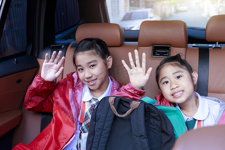两个快乐的学生在享受汽车公路旅行的同时举手和动作。