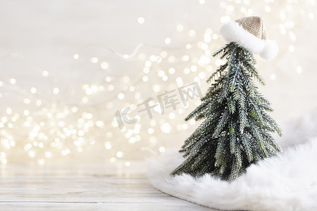 粉金色计灯管倒计时摄影照片_圣诞小树和金色灯光散景。