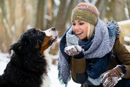 女人在雪地里和她的狗玩耍