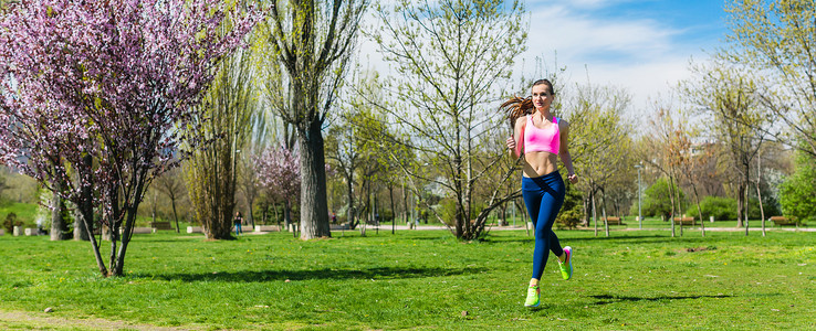 女人为了更好的健身而在春天穿过公园跑步