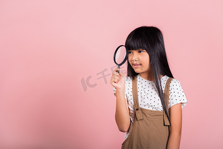 放大镜小孩摄影照片_10 岁的亚洲小孩通过放大镜看很有趣