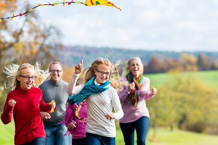 一家人放风筝摄影照片_一家人在秋天的森林里散步放风筝