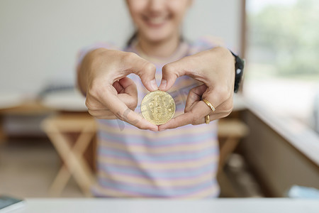 女性钱摄影照片_Cryptocurrency 是数字货币，女性手握计算机准备好的比特币硬币来投资来自未来数字或想象世界的资产。 