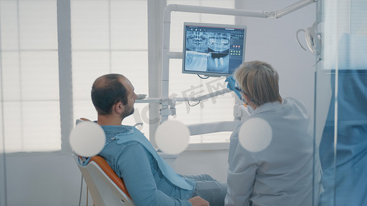 成熟的牙医指着显示器上的牙齿放射照相术
