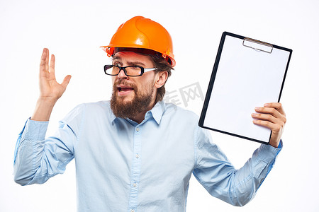 安全施工海报摄影照片_工程师橙色头盔安全专业手册在手工裁剪视图中