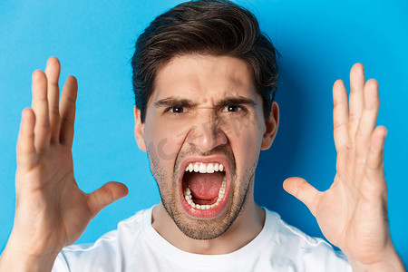 男人的头像表现出愤怒和沮丧，愤怒的脸大喊大叫，站在蓝色背景上