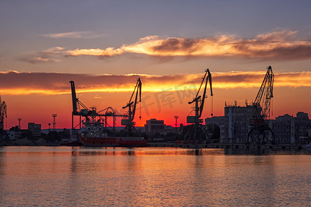 令人惊叹的红色夕阳下港口起重机的剪影。