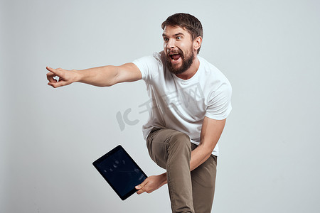 手拿平板电脑摄影照片_手拿平板电脑的情绪化男人触摸屏新技术浅色背景裁剪视图复制空间