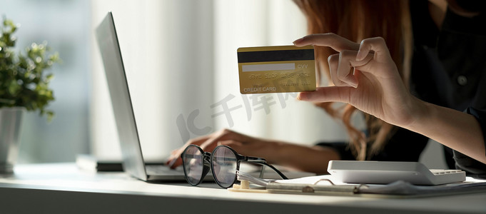 亚洲女性在电脑上查看网上订单详情，并使用电脑上输入的信用卡信息。