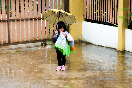 雨中撑着伞喝牛奶的小女孩