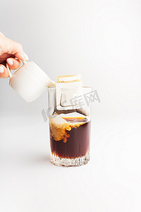 入杯摄影照片_滴滤咖啡袋将咖啡粉放入杯中，将热水倒入滤纸滴滤咖啡中冲泡。