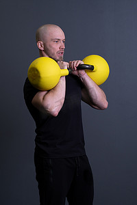 有黄色壶铃健身房的匿名黄色男性，为运动青少年挑选橡胶举重、越南健身。