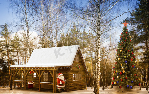 圣诞树木摄影照片_圣诞老人在树林里的小屋和一棵圣诞树。