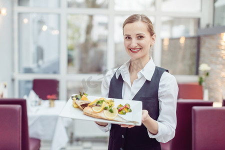 服务员酒店摄影照片_一家不错的餐厅的女服务员提供一道美味的菜肴