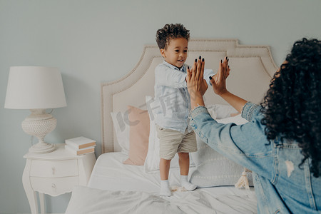 可爱快乐的美国黑人小孩在家里的卧室里和妈妈玩耍
