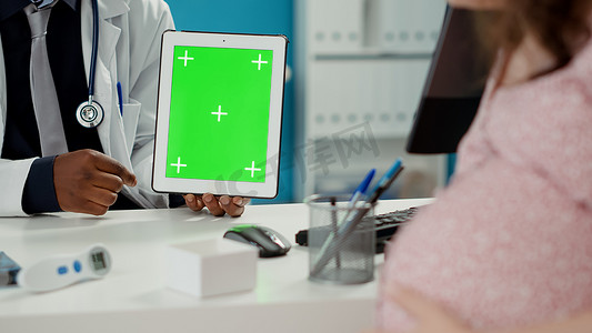 拿着绿屏背景的数字平板电脑的医生
