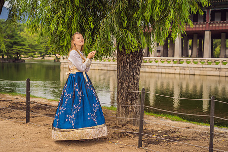 韩服图腾摄影照片_在韩国宫殿穿着韩服的年轻白人女游客。