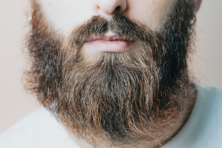 剃胡子的男人摄影照片_留胡子的帅哥剃胡子，年轻的白种人留胡子的男人在隔离期间在家里修剪胡须。