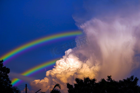 彩虹出现在雨后的天空中并返回到晚霞上