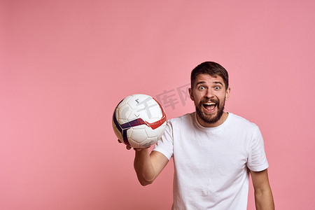 在粉红色背景能量上拿着足球的男人用他的手教练情绪模型指手画脚