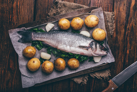 烤盘上塞满酸模的新鲜海鲈鱼配土豆和洋葱