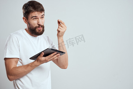 情绪化的男人手拿平板电脑触摸屏新技术浅色背景裁剪视图复制空间